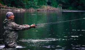 Man standing in water fishing.