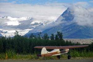 Small airplane on runway with large mountain in background.