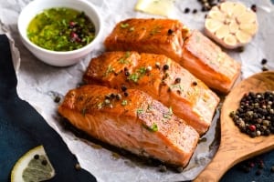 A well prepared salmon entree surrounded by olive oil mixed with various seasonings.