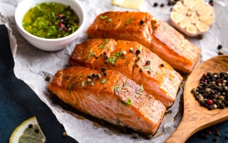 A well prepared salmon entree surrounded by olive oil mixed with various seasonings.