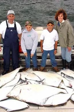 A family of anglers with a pile of Alaskan halibut.