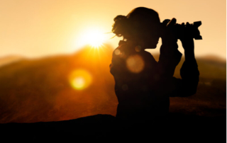 The silhouette of a photographer adjusting her lens during an photography tour near Angoon, Alaska.