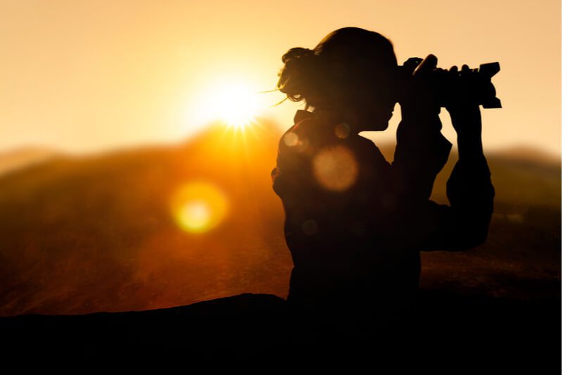 The silhouette of a photographer adjusting her lens during an photography tour near Angoon, Alaska.