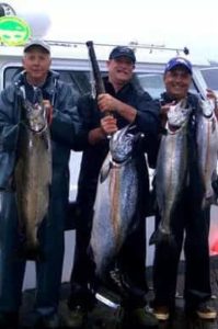 A trio of anglers display their bounty of salmon while sport fishing in Alaska.