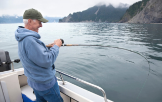 A seasoned angler enjoys his all-inclusive Alaska vacation as reels in a large salmon.
