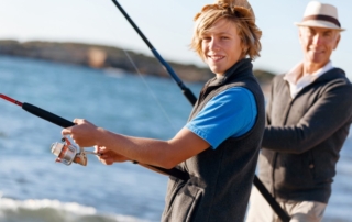 Family Fishing Trips: A young teenage boy fishing with his grandfather in Alaska.